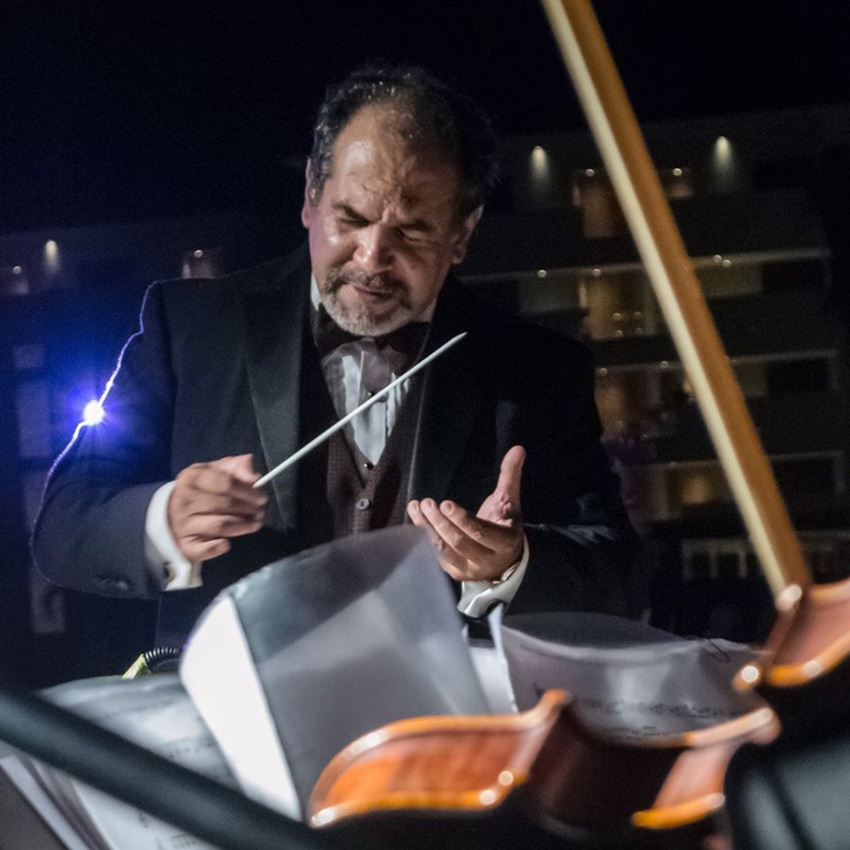 Mario Monroy dirige con la batuta, frente a la partitura